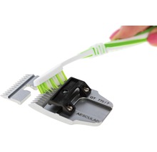 Eine Hand reinigt mit einer Bürste einen Scherkopf.