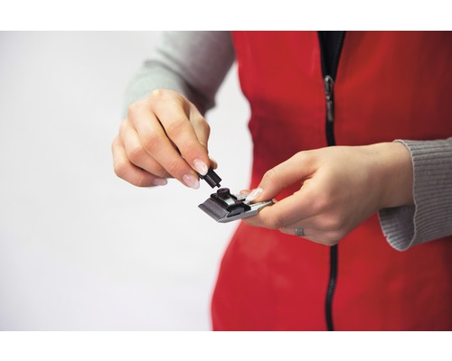 Frau setzt eine Haarschneidemaschine zusammen