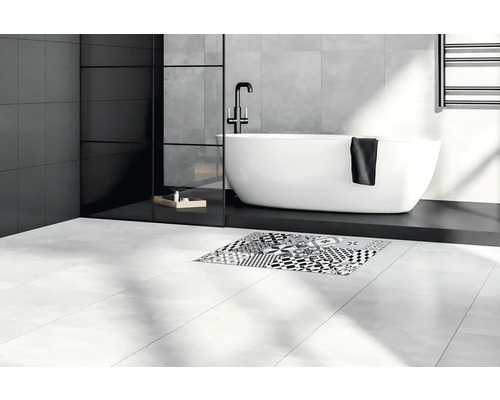 Salle de bains lumineuse avec baignoire, carrelage et tapis de bain à motifs