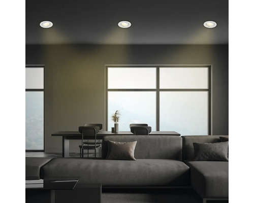 Wohnzimmer mit Deckenleuchten, Sofa, Tisch und Stühlen.