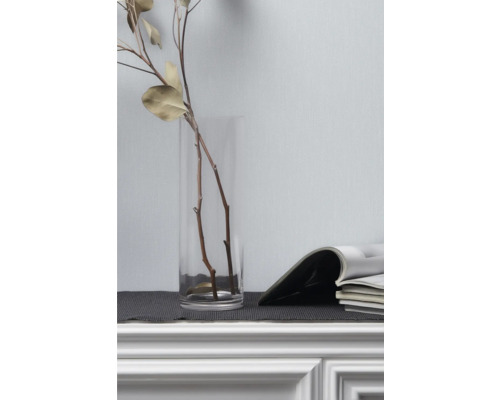 Dekorative Äste in Glasvase neben Zeitschriften auf Kommode