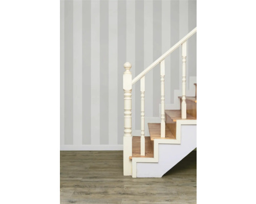 Treppe mit Holzstufen und weissem Geländer vor gestreifter Wand