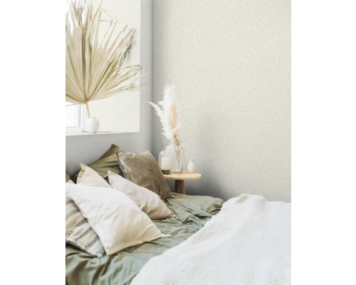 Chambre avec papier peint à motifs, lit avec coussins et objets de décoration.