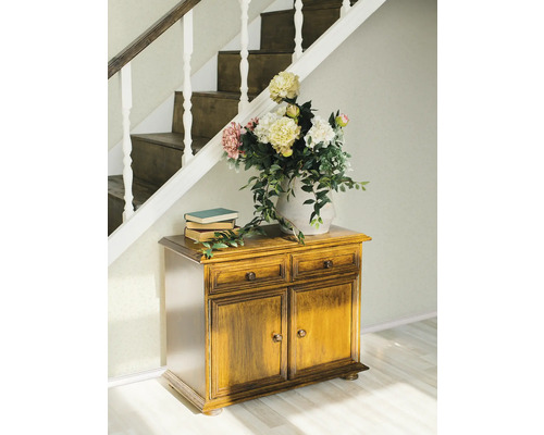 Scène avec commode en bois, livres et fleurs sous un escalier