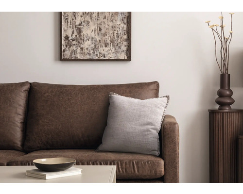 Scène de salon avec canapé en cuir marron, coussin décoratif, table, décoration et œuvre d''art