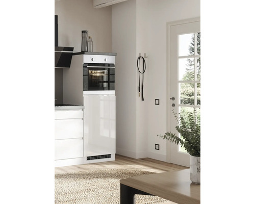 Cuisine claire avec four, armoires blanches et plancher en bois.