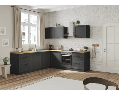 Moderne Küche mit grauen Schränken, Holzoberflächen und Geräten vor einer Ziegelwand.