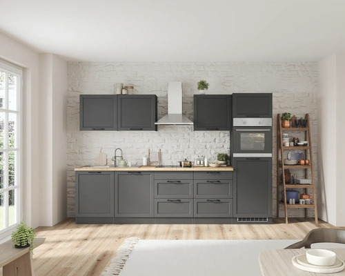 Cuisine moderne avec armoires grises, hotte aspirante, four et étagère en bois contre un mur de briques blanches