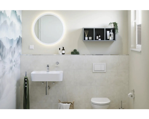 Salle de bain avec lavabo, miroir éclairé, étagère et toilettes.