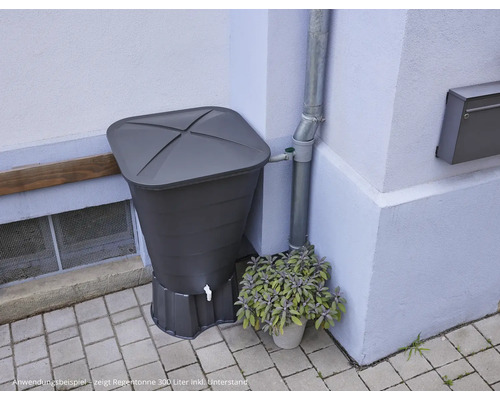 Regentonne mit Deckel und Ablaufhahn neben einem Fallrohr an einer Hauswand