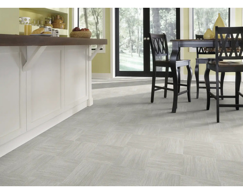 Heller Raum mit Bodenfliesen in quadratischer Anordnung und Kücheninsel mit Barhockern