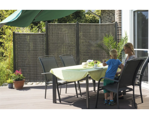 Clôture de protection visuelle en plastique tressé et table de jardin avec chaises sur une terrasse