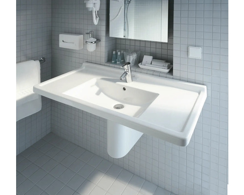 Weisses Waschbecken mit Armatur im Badezimmer vor Fliesenwand.