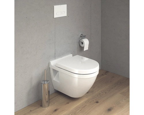 Szene mit wandhängendem WC, Betätigungsplatte, Toilettenpapierhalter und Toilettenbürste in einem Badezimmer