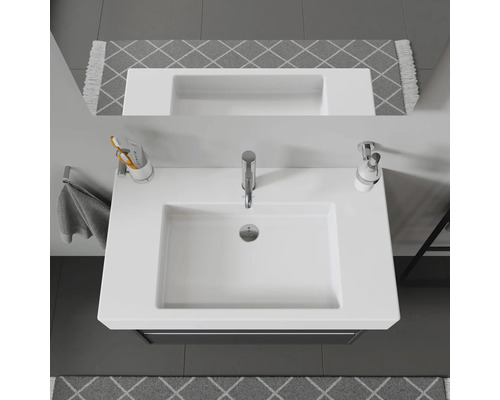 Vue de dessus d''un lavabo blanc avec robinetterie, distributeur de savon et porte-brosses à dents dans la salle de bains