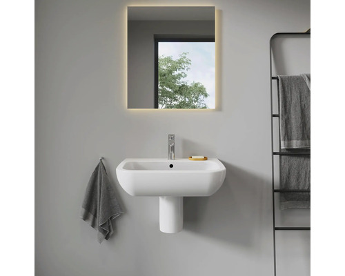 Salle de bains moderne avec lavabo, colonne de lavabo et miroir éclairé