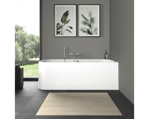 Salle de bain moderne avec baignoire îlot, robinetterie et images de plantes.