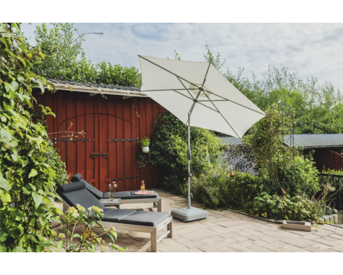 Scène de jardin avec parasol, chaises longues et cabanon en bois rouge.
