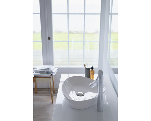 Salle de bain moderne avec lavabo à poser et robinet devant une fenêtre.