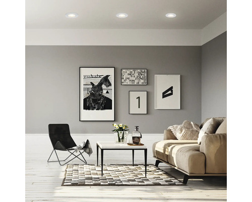 Salon avec plafonniers, canapé, fauteuil, table et tableaux au mur