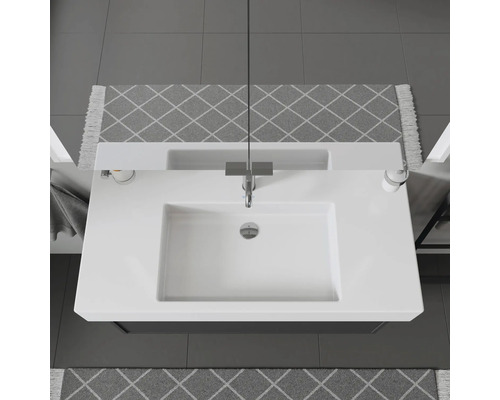 Vue de dessus d''un lavabo avec robinet, distributeur de savon et tapis à motifs dans la salle de bains.