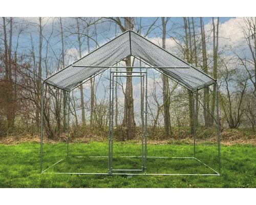 Freistehender Hühnerzaun aus Metall mit Maschendrahtdach auf einer Wiese vor Bäumen.