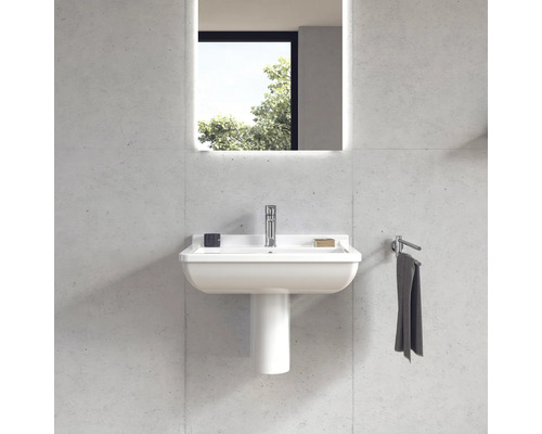 Badezimmer mit Waschbecken, Waschtischsäule, Armatur, Handtuch und beleuchtetem Spiegel
