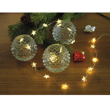Décoration avec guirlande lumineuse étoile, bougies chauffe-plat et branche de sapin de Noël sur table en bois