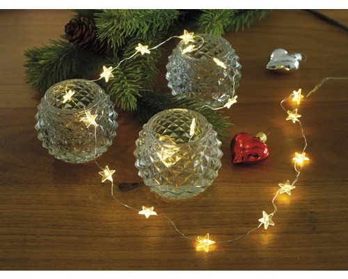 Décoration avec guirlande lumineuse étoile, bougies chauffe-plat et branche de sapin de Noël sur table en bois