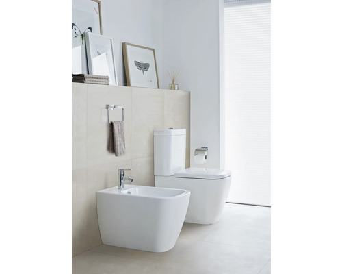 Salle de bains moderne avec bidet et toilettes en blanc, plus porte-serviettes et décorations