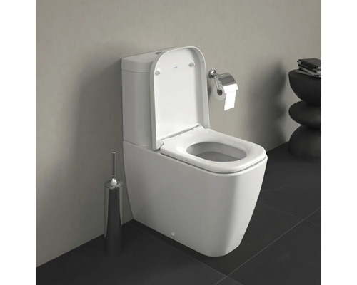 WC au sol blanc avec couvercle de toilette ouvert et porte-papier toilette dans la salle de bain