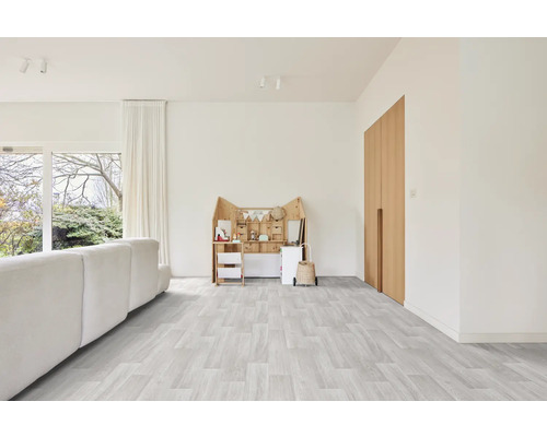 Salon lumineux avec canapé, meubles de jeux et portes en bois sur un plancher en bois gris clair.