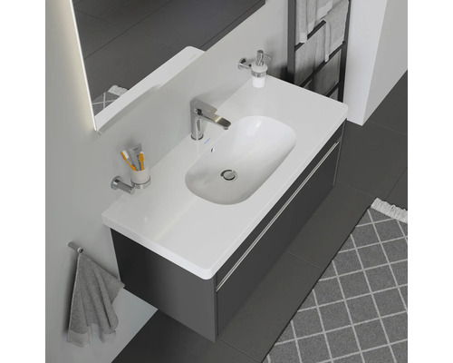 Salle de bains moderne avec lavabo, meuble sous-vasque, robinet, distributeur de savon, serviette et autres accessoires de salle de bains.