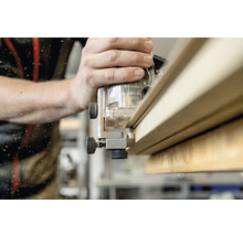 Une défonceuse est utilisée pour travailler une planche de bois.