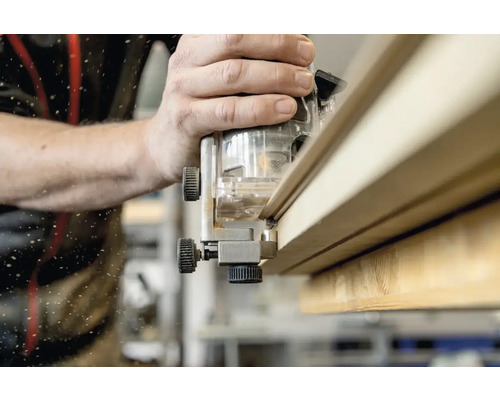 Une défonceuse est utilisée pour travailler une planche de bois.