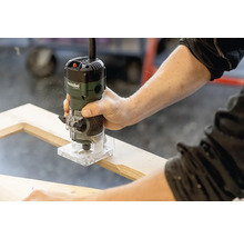 Une personne utilise une défonceuse Metabo sur un cadre en bois.