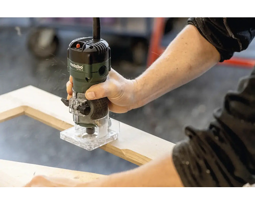 Une personne utilise une défonceuse Metabo sur un cadre en bois.