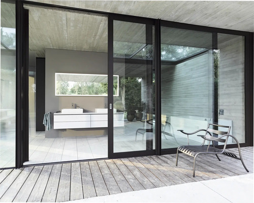 Salle de bains avec lavabo, miroir et portes coulissantes donnant sur une terrasse avec des sièges