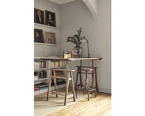 Espace de travail lumineux avec des tréteaux en bois comme pieds de table, étagère avec des livres et des décorations