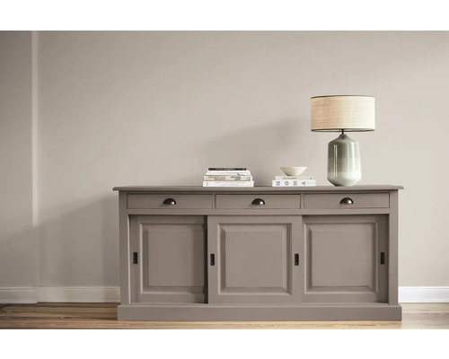 Commode avec portes coulissantes, tiroirs, lampe et décoration sur un plancher en bois