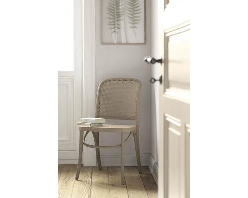 Chaise avec dossier en rotin et livre sur l''assise devant une décoration murale