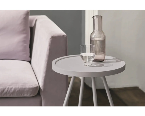 Table d''appoint avec carafe d''eau et verre à côté d''un canapé