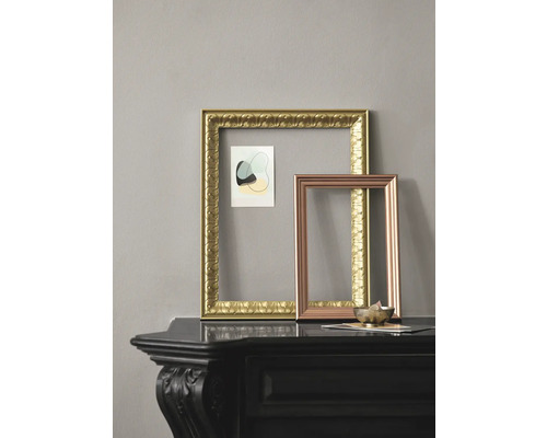 Deux cadres photo vides en or et en cuivre sur une étagère noire.