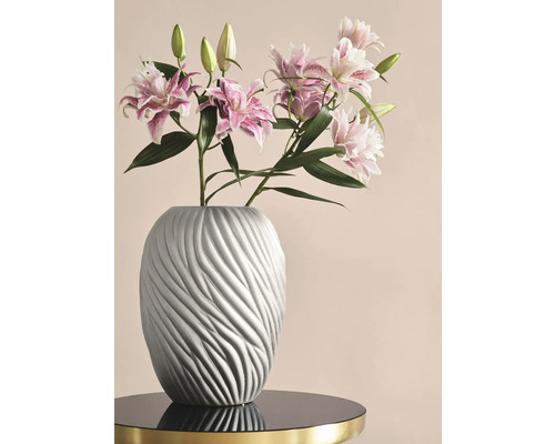 Lys dans un vase gris avec une structure ondulée sur une table
