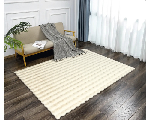 Wohnzimmer mit Couch und gemustertem, rechteckigem Teppich.