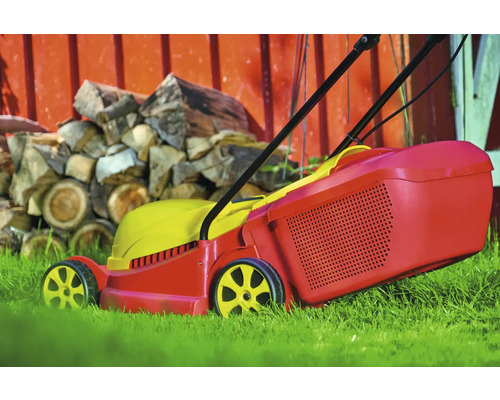 Tondeuse à gazon dans le jardin avec une pile de bois