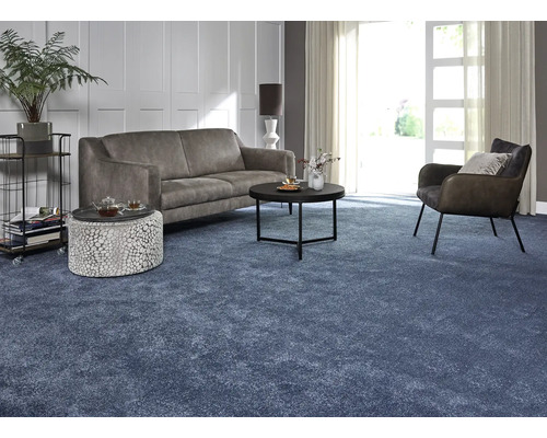 Wohnzimmer mit Sofa, Sessel, Couchtisch und blauem Teppich