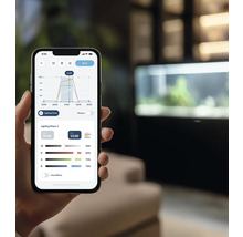 Un smartphone affiche une application pour contrôler l''éclairage d''aquarium avec des diagrammes et des paramètres.