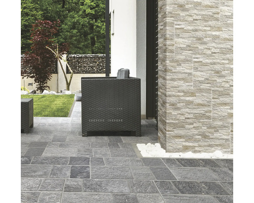 Terrasse avec pavés et revêtement mural aspect pierre ainsi que des sièges