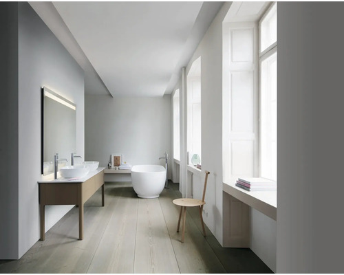 Salle de bains lumineuse avec double vasque, baignoire îlot et fenêtre.